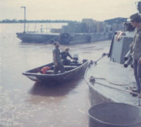 "The ammo guy". I wish I could remember his name. Maybe someone can identify him for me. The Benewah had an ammo barge tied to it trailing about 150 yards downstream when it was anchored near Tan Chau in 1970. This picture is taken from the stern of the HQ5166 boat as we and another VN boat are taking on ammunition.