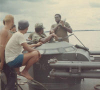 This is also near the Benewah. This is a good view of the 3.5 inch rockets that were fitted on the forward 20MM mount on the ASPBs during 1970-71. The 2 guys in green are Gunners Mates from the Benewah. They were sighting in the new tubes before a patrol. The shell seen on the shoulder on one of the GMs has two copper rings on it. They made contact with two copper protrusions in the tube. The rocket was fired by selecting the tube with a rotary switch in the turret and stepping on the trigger, which sent an electric charge to the shell. The range was short, about 200 yards maximum and we only had the anti-tank shells, which were good for bunkers, but it would have been 
nice to have some anti-personnel type shells.